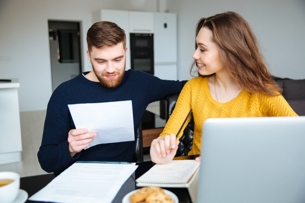 Happy young couple calculating bills at home Happy young couple calculating bills at home