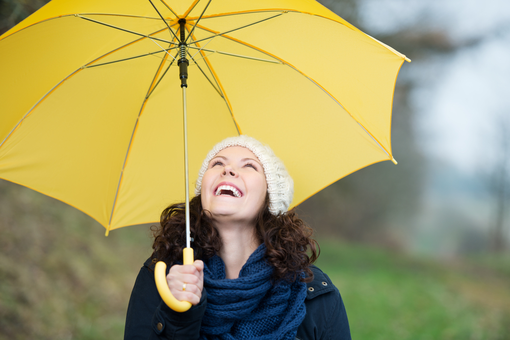 Happy young woman in winter clothes holding yellow umbrella in park Happy young woman in winter clothes holding yellow umbrella in park